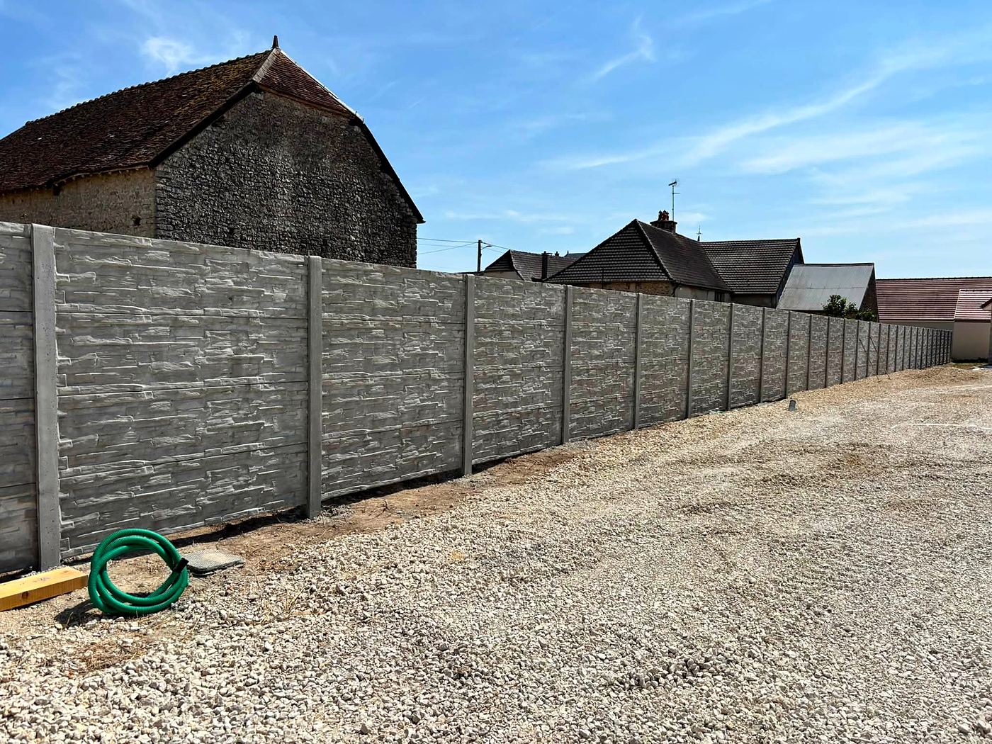 Clôture en plaques béton le long d'une cour en gravier